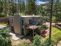 Contemporary stucco home featuring a deck, covered parking, and lush, mature trees at 6100 Apache Dr, Larkspur, CO 80118