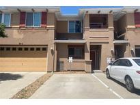 A front exterior view of a tan two-story townhome with a garage and a balcony under a clear blue sky at 9300 E Florida Ave # 608, Denver, CO 80247