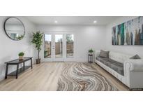 Bright living room with wood floors, white sofa, and glass doors leading to the patio at 2232 Coronado Pkwy # B, Denver, CO 80229
