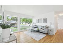 Bright living room with a comfortable gray sofa, large windows, and hardwood floors for a modern feel at 5445 Nebraska Way, Denver, CO 80246