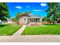 Charming single-story home with a well-manicured lawn, sidewalk and traditional architectural details at 458 Cherry St, Hudson, CO 80642