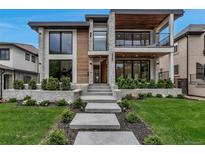 Stunning modern home featuring a stone and wood facade, balcony, manicured lawn, and inviting concrete entryway at 220 Glencoe St, Denver, CO 80220