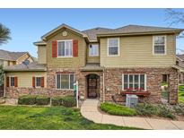 Charming townhome with a stone facade, red shutters, a well-manicured lawn, and a welcoming front entrance at 15496 W 66Th Dr # G, Arvada, CO 80007