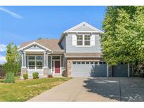 Charming two-story home featuring a well-maintained lawn, classic architectural details, and a welcoming red front door at 13971 Star Creek Dr, Broomfield, CO 80023