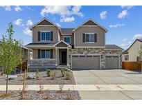 Inviting two-story home with stone accents, a three-car garage, and a charming front porch at 25214 E Warren Pl, Aurora, CO 80018