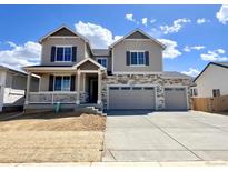 Two-story home featuring a two-car garage, stone accents, gray siding and shutters, and a cozy front porch at 25214 E Warren Pl, Aurora, CO 80018