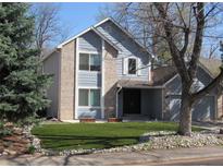 Charming two-story home featuring blue siding, brick accents, well-maintained lawn and mature trees at 12381 E Vassar Dr, Aurora, CO 80014