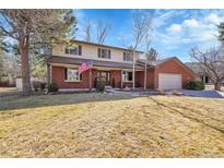 Charming two-story brick home featuring a well-manicured lawn and an inviting covered front porch at 5158 W Lake Pl, Littleton, CO 80123