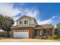 Charming two-story brick home featuring an attached two-car garage, well-manicured lawn, and beautiful blue skies at 19033 E 22Nd Cir, Aurora, CO 80011