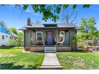 Charming home with a cozy front porch, green lawn, and distinctive purple door at 4321 Winona Ct, Denver, CO 80212