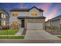 Charming two-story home features a stone facade, white siding, and a spacious two-car garage at 17276 E 103Rd Ave, Commerce City, CO 80022