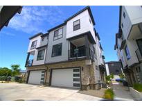 Modern townhome featuring two-car garage, stone accents, and private balcony at 2010 S Holly St # 3, Denver, CO 80222