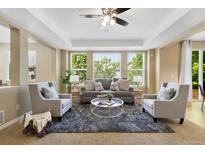 Bright living room features large windows, a ceiling fan and comfortable seating arrangement at 4821 Bluegate Dr, Highlands Ranch, CO 80130
