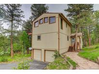 Tan two-story home with a two car garage, wood trim, and a stone walkway at 9209 William Cody Dr, Evergreen, CO 80439
