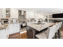 Open kitchen features stainless steel appliances, a large island with seating, and pristine white cabinetry at 5265 S Cathay Way, Centennial, CO 80015