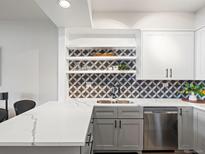 Modern kitchen features updated appliances, grey and white cabinets, quartz countertops, and decorative tile backsplash at 345 Fillmore # 407, Denver, CO 80206