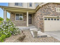 Charming stone accented house with a cozy front porch and a decorative wreath on the front door at 6108 S Harvest Ct, Aurora, CO 80016