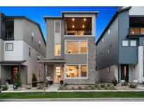 Contemporary three-story home featuring stone accents, a private balcony, and well-maintained landscaping at 12270 W 57Th Ave, Arvada, CO 80002