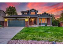 Charming two-story home with manicured lawn and a two-car garage, set against a stunning sunset backdrop at 2587 S Flanders Ct, Aurora, CO 80013