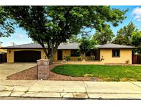 Charming single-story home featuring a well-manicured lawn, mature trees and an attached two car garage at 6376 Lamar Pl, Arvada, CO 80003