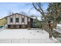 Ranch style home with a fenced yard, snow covered lawn, and mature trees at 15895 E 17Th Pl, Aurora, CO 80011