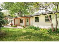 Inviting front yard with lush green grass and colorful landscaping, leading to the charming front entrance at 6891 W Eldorado Pl, Lakewood, CO 80227