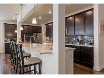 Modern kitchen features dark cabinetry, stainless steel appliances, and breakfast bar seating at 848 Sandstone Cir, Erie, CO 80516