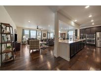 Open-concept living room and kitchen featuring dark hardwood floors and lots of natural light at 848 Sandstone Cir, Erie, CO 80516