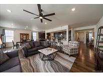 Spacious living room open to kitchen, featuring a ceiling fan and hardwood floors at 848 Sandstone Cir, Erie, CO 80516