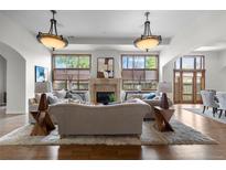Elegant living room featuring hardwood floors, a stone fireplace, and large windows providing ample natural light at 4525 King St, Denver, CO 80211