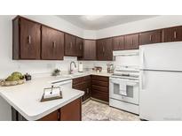 Efficient kitchen with wooden cabinets, white appliances, and ample counter space at 3450 S Poplar St # 109, Denver, CO 80224