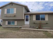 Split-level home features white trim, neutral siding and a concrete walk-up entrance, offering classic curb appeal at 8353 Gaylord St, Denver, CO 80229