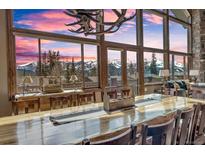 Bright dining room with a large custom table and floor to ceiling windows offering mountain views at 185 S Fuller Placer Rd, Breckenridge, CO 80424