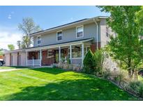Charming two-story home features a lovely front porch, brick accents, and a well-manicured lawn at 6150 Reed St, Arvada, CO 80003