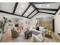 Bright living room with vaulted ceiling, hardwood floors, and a view into the kitchen at 7910 E Bethany Pl, Denver, CO 80231