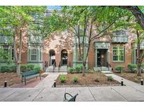 Brick townhouse exterior with front yard landscaping and trees providing shade at 8735 E 29Th Pl, Denver, CO 80238