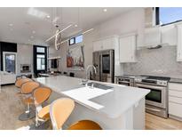 Bright, modern kitchen features stainless steel appliances, white cabinets, and a large center island with seating at 2442 Champa St, Denver, CO 80205