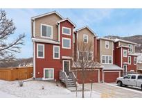 Two-story townhome with a covered entry and red and tan siding on a snowy day at 2534 Valley Oak Rd, Castle Rock, CO 80104