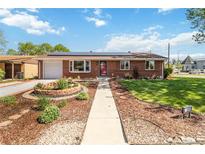Charming brick home featuring a beautifully landscaped front yard and solar panels on the roof at 5593 E Center Ave, Denver, CO 80246