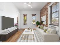 Bright living room featuring exposed brick, wood floors, large windows, and a modern white sofa at 1103 Lipan St, Denver, CO 80204