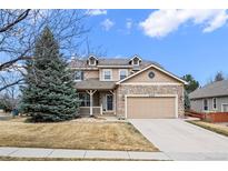 Charming two-story home featuring a stone facade, covered porch, manicured lawn, and a two-car garage at 4463 Eagle River Run, Broomfield, CO 80023