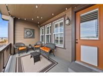 Inviting porch with wicker furniture, string lights, and an orange front door at 4475 Hidden Gulch Rd, Castle Rock, CO 80104