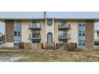 Exterior of multi-Gathering unit with balconies, stone columns, and winter landscaping at 12174 Melody Dr # 203, Westminster, CO 80234