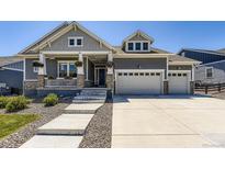 Charming two-story home featuring a welcoming front porch, gray siding, stone accents and a three car garage at 3344 Carabiner St, Castle Rock, CO 80108