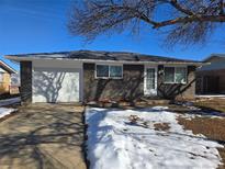 Charming single-story brick home with attached garage and snow in front yard on sunny day at 26 S Gay Dr, Longmont, CO 80501