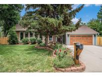 Charming brick home featuring a well-manicured front yard, mature landscaping, and an attached two-car garage at 14887 W 49Th Pl, Golden, CO 80403
