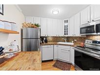 Well-lit kitchen featuring stainless steel appliances, white cabinetry, and granite countertops at 1390 N Emerson St # 406, Denver, CO 80218