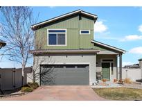 Charming two-story home featuring a green facade, gray garage door, and well-maintained front yard at 19055 E 55Th Ave, Denver, CO 80249