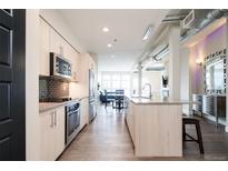 Open concept kitchen with stainless steel appliances, island with granite countertop, and dining area at 3198 Blake St # 502, Denver, CO 80205