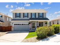 Charming two-story home features a well-manicured lawn, grey siding, and a welcoming front porch at 11866 High Desert Rd, Parker, CO 80134